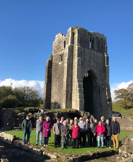 Delegates at the National Dialect Festival visited Shap Abbey; warmly dressed group of people standing on a lawn in sunshine